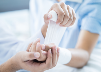 A Provider wrapping a wound on a patient's arm.