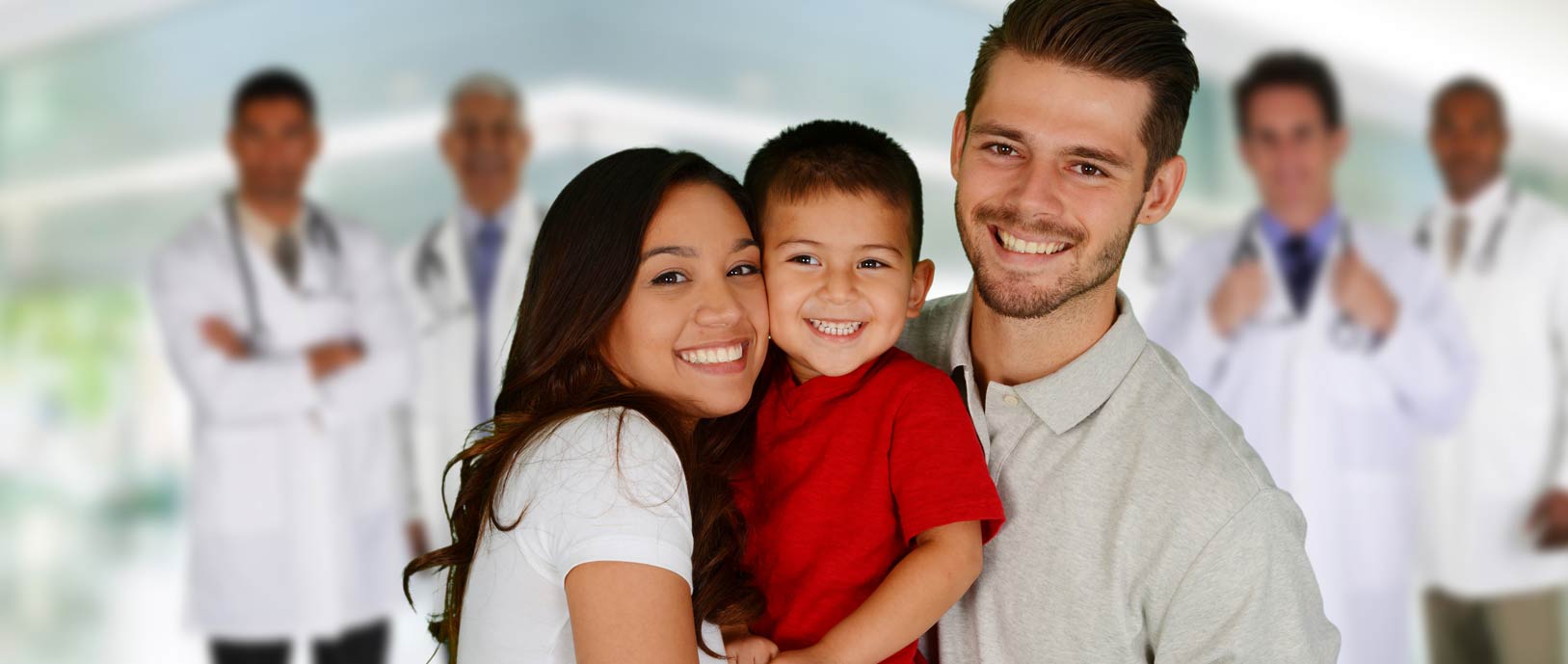 Banner picture of a young couple holding their son and smiling. There is four male Physicians in the background faded out.
