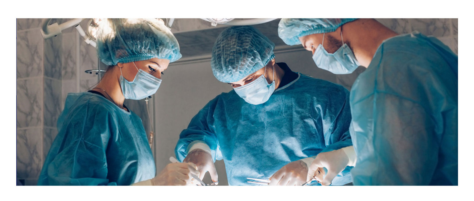 Banner picture of a doctor and two surgical assistants performing an operation. They are dressed in full protective gear. There is two males and one female.