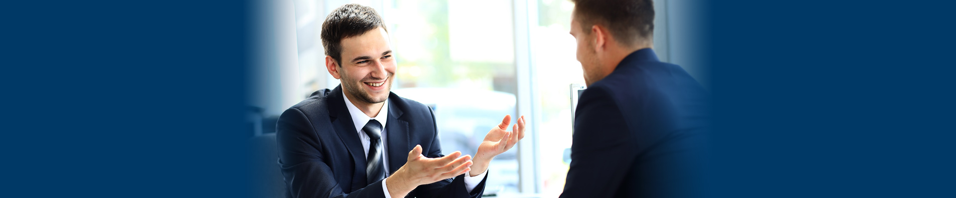 Banner picture of a male Employee listening to male HR personnel talk.