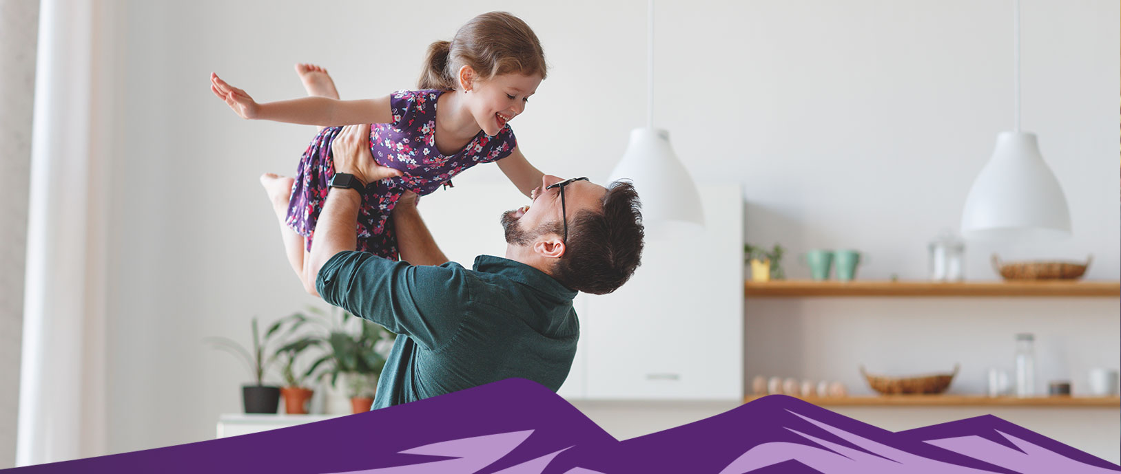 A father is holding his daughter in the air as if she is flying