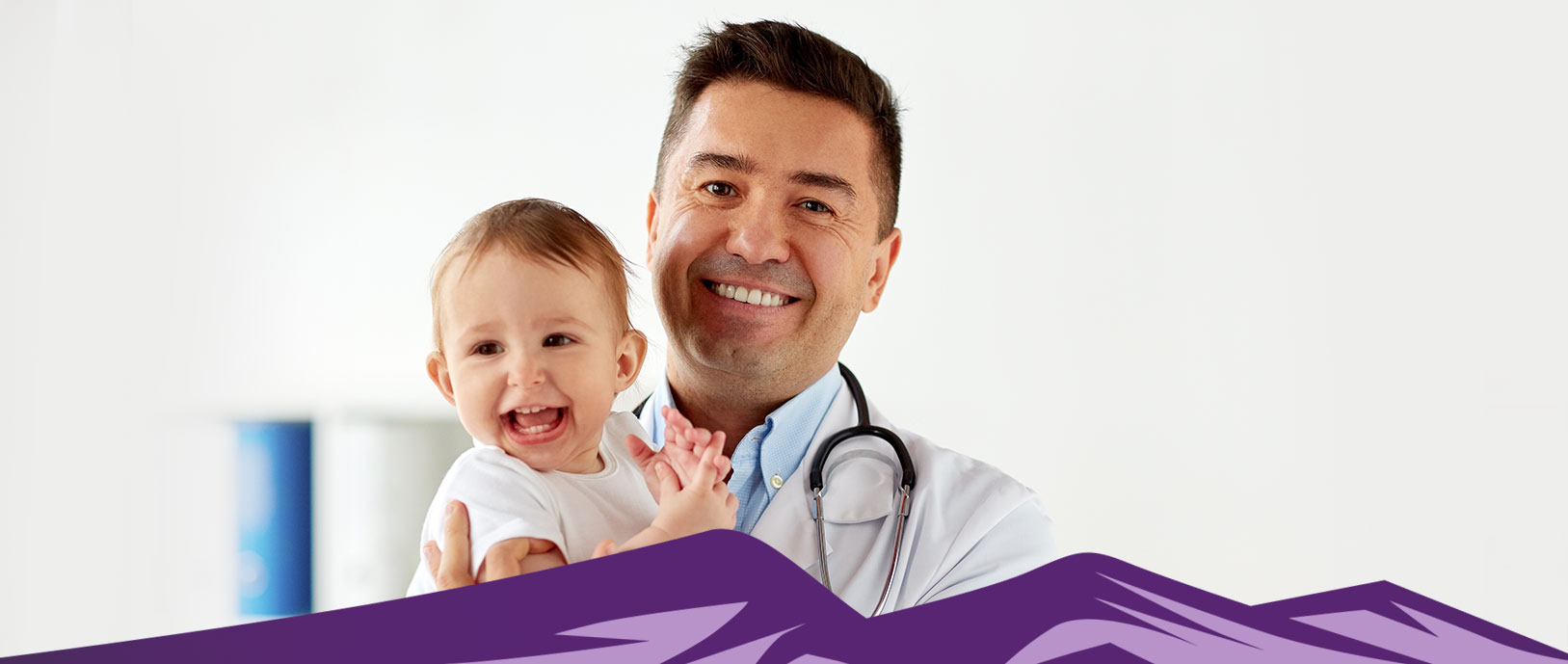 A smiling physician is holding a happy baby