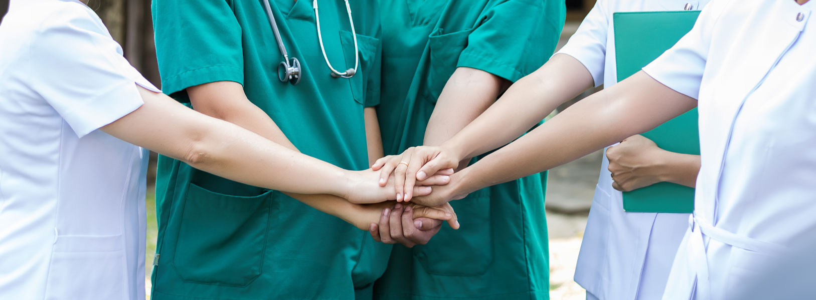 A group of medical employees are holding their hands in a team effort