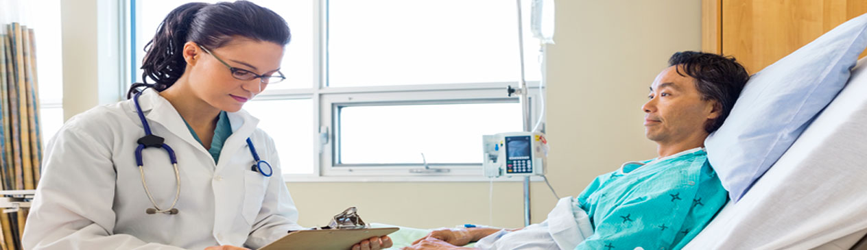 Banner Picture of a male patient sitting up in a hospital bed and a female Physician sitting on the edge of the bed looking down at the patient's chart.