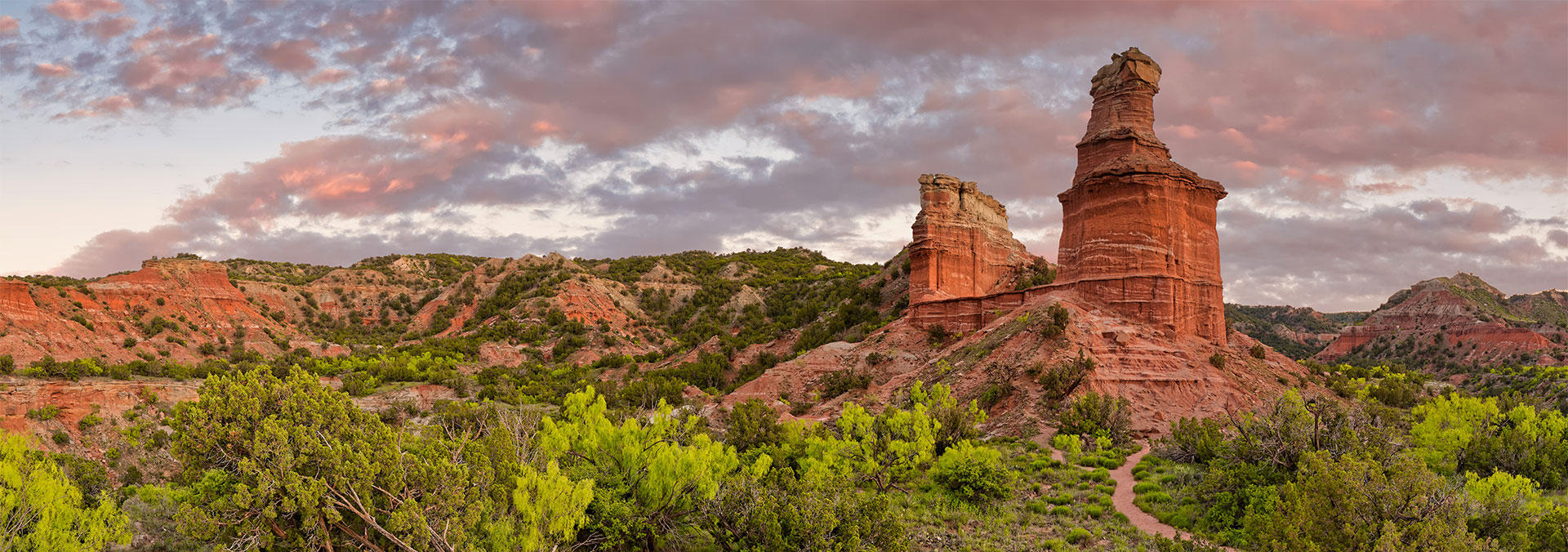 Banner picture of red rock mountains and a trail at sunset.