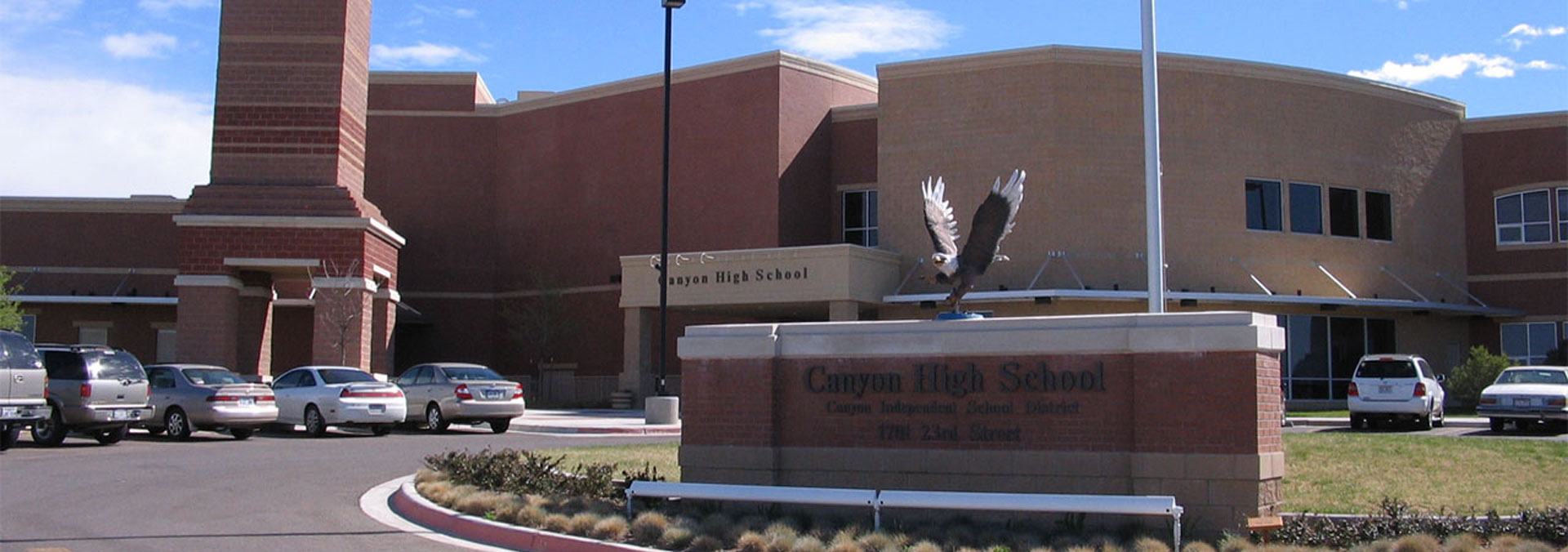 Banner picture of the Front of Canyon High School and a sign outside of the High School of an Eagle Mascot sculpture,