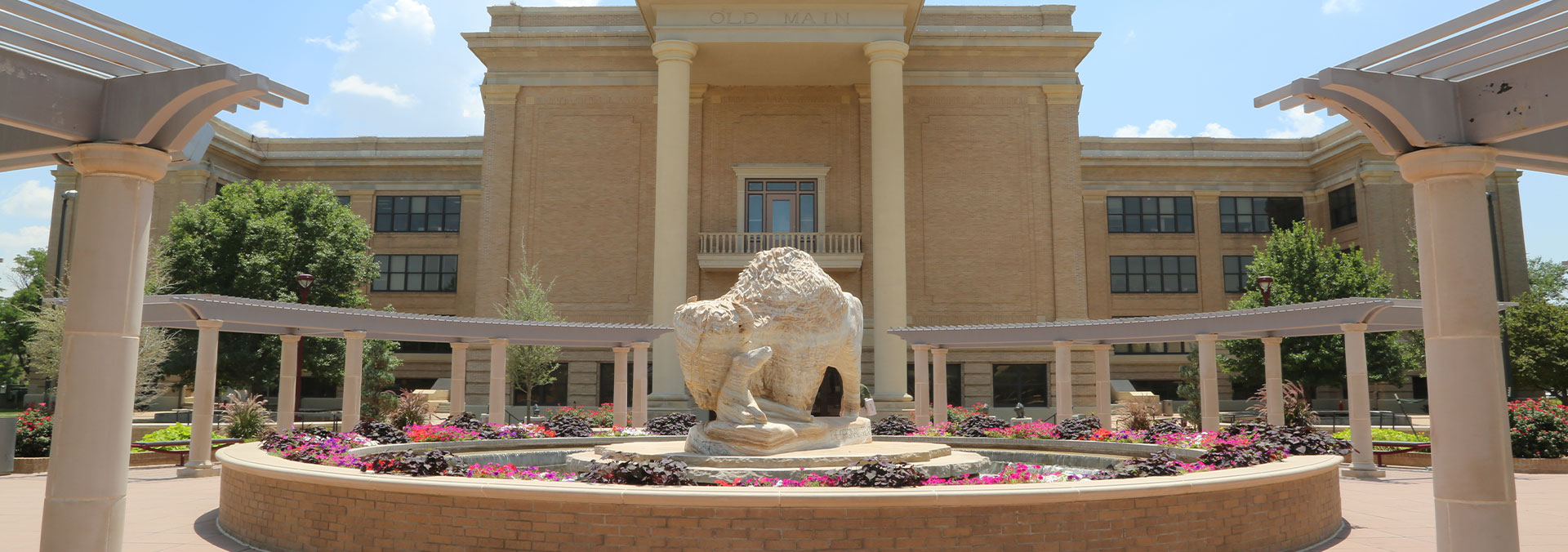 Banner picture of beautiful courtyard of a circle fountain in the center and a buffalo statue and baby buffalo.
