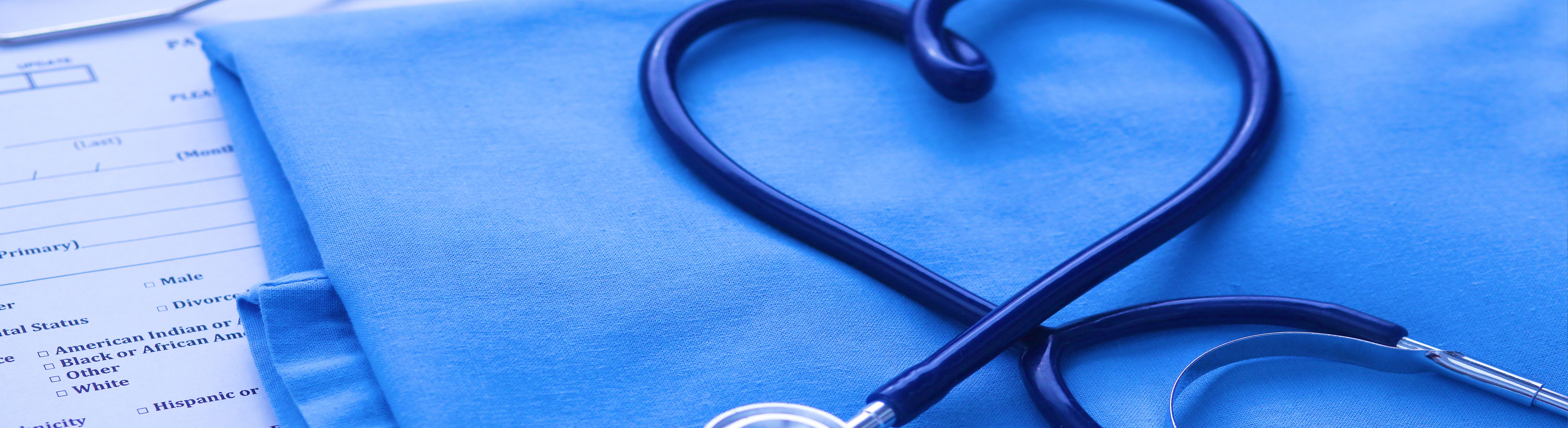 Banner picture of Medical paper work with scrubs on top of it and a stethoscope positioned like a heart
