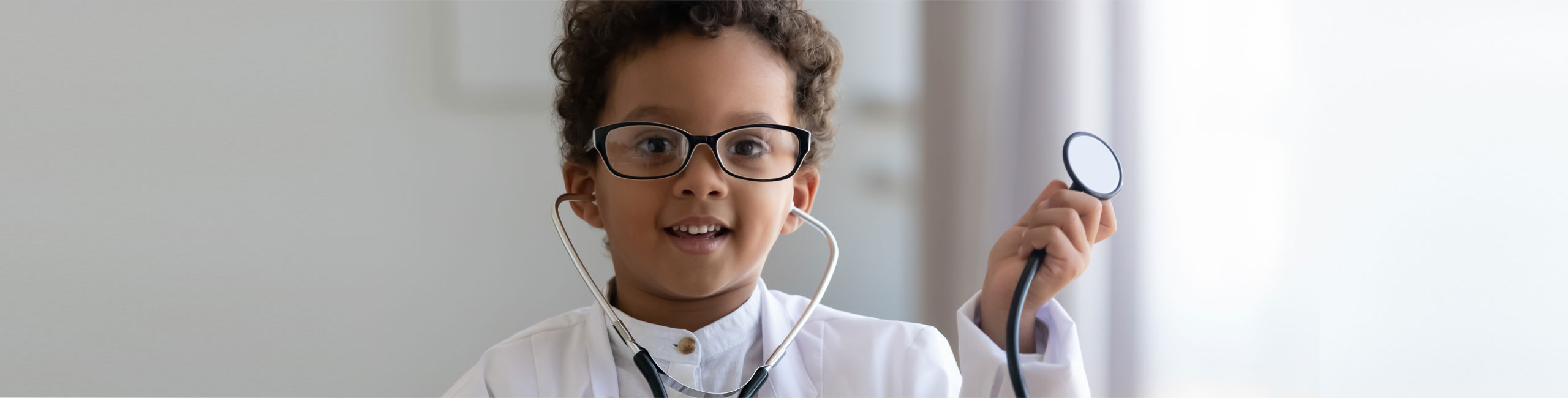Banner picture of a little boy with a stethoscope in his ears and holding the stethoscope out.