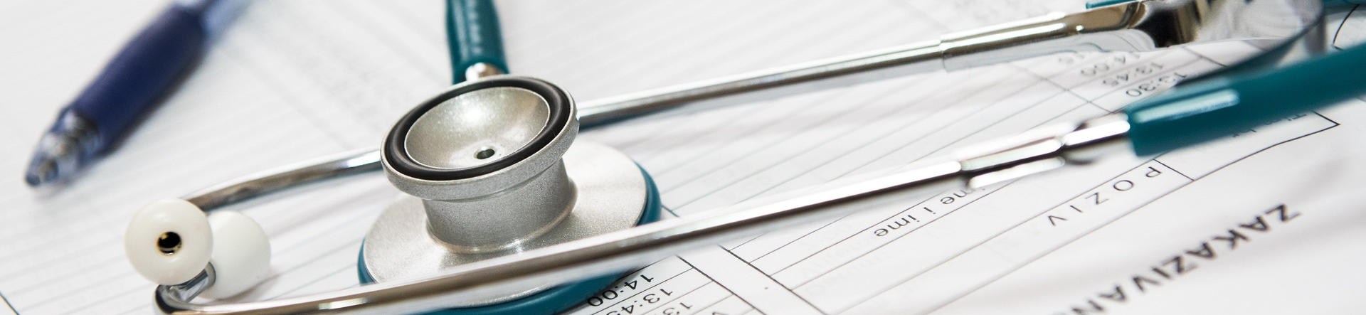 Banner picture of a stethoscope lying on top of a form with a pen sitting next to it.