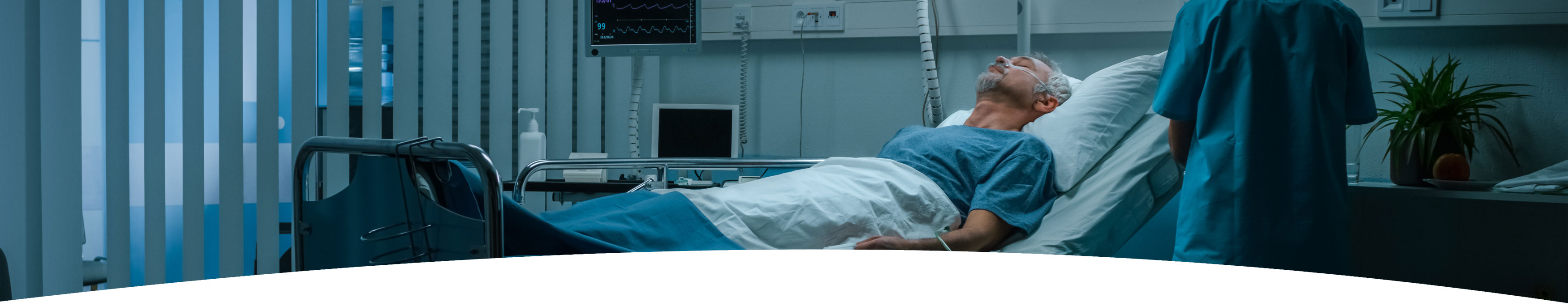 Banner picture of a male patient lying down in a swing bed sleeping and wearing an oxygen nasal cannula. There is a Nurse standing next to his bedside by the bedside table (back side of them in scrubs from shoulders down).