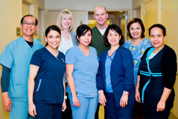 Picture of Medical Staff standing in the Hospital hallway. There is six females and two males smiling in the picture.