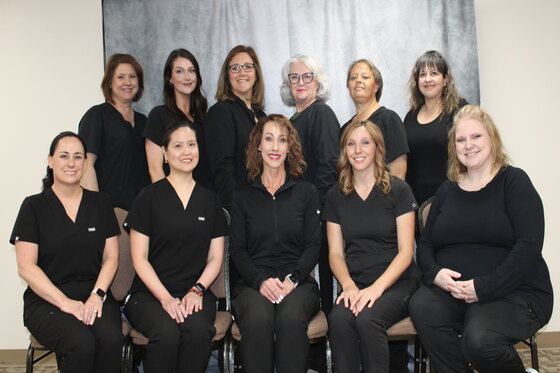 Hospital staff memebers sitting next to each cother, smiling.