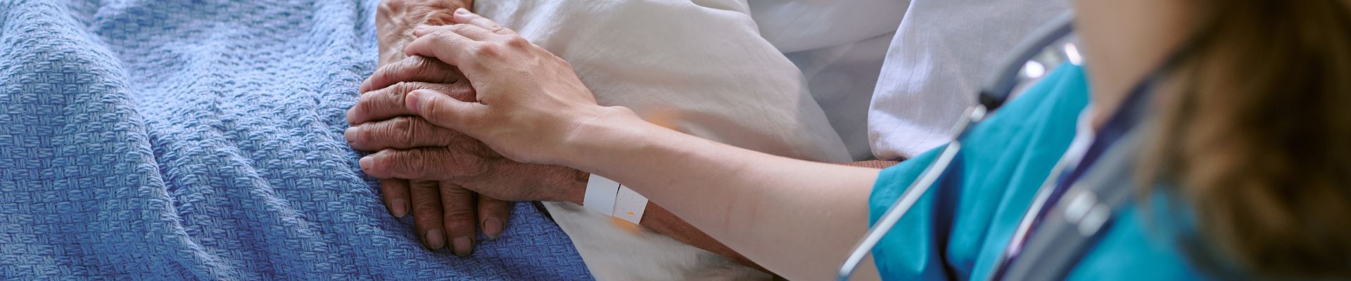 holding hand of patient  in a medical bed